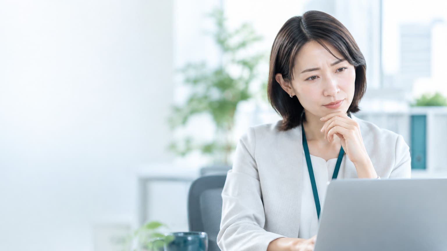 オフィスでパソコンを前に考える人物のイメージ画像
